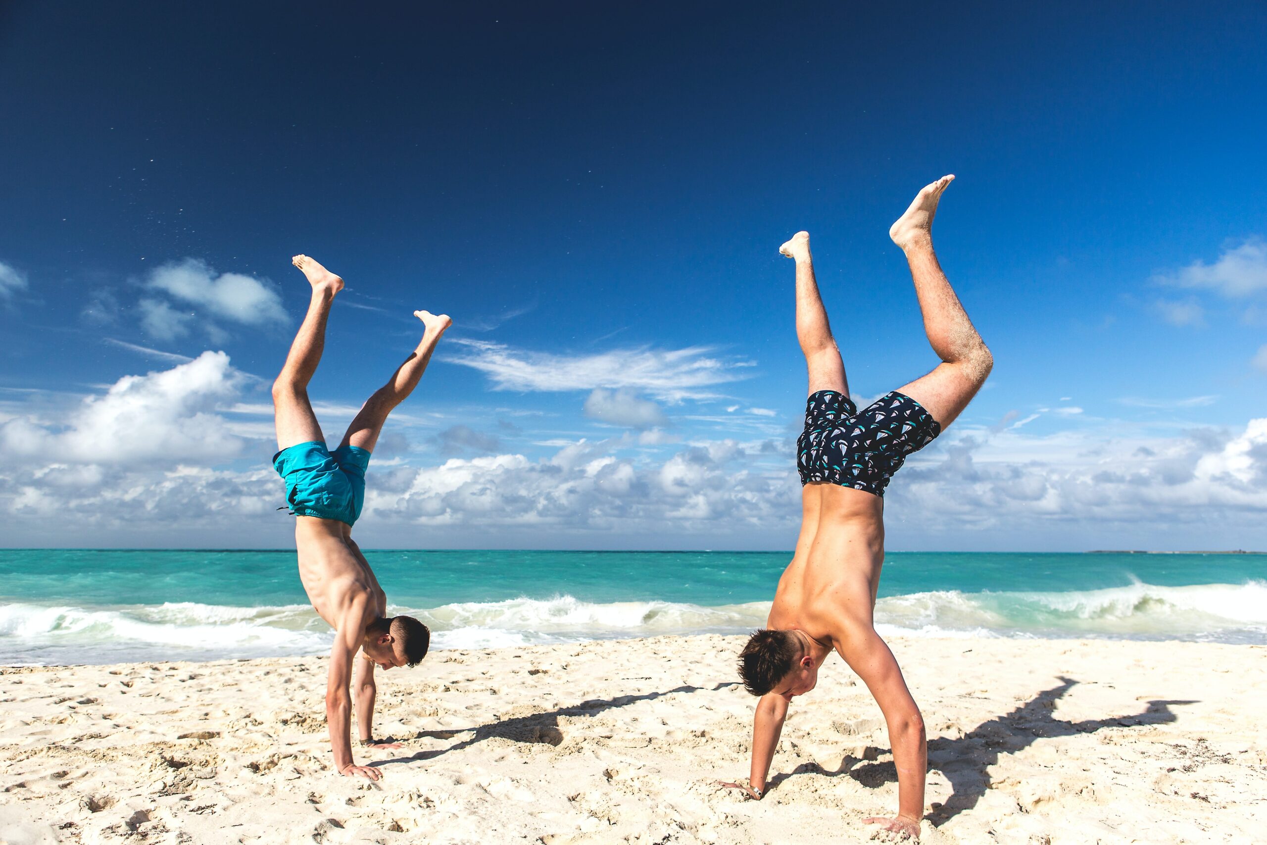Two men doing a handstand on a beach in Cuba